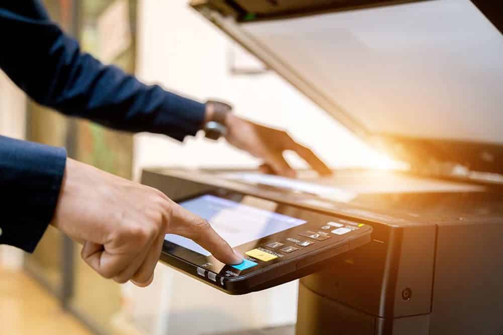 A person is using a printer in an office while providing IT services.