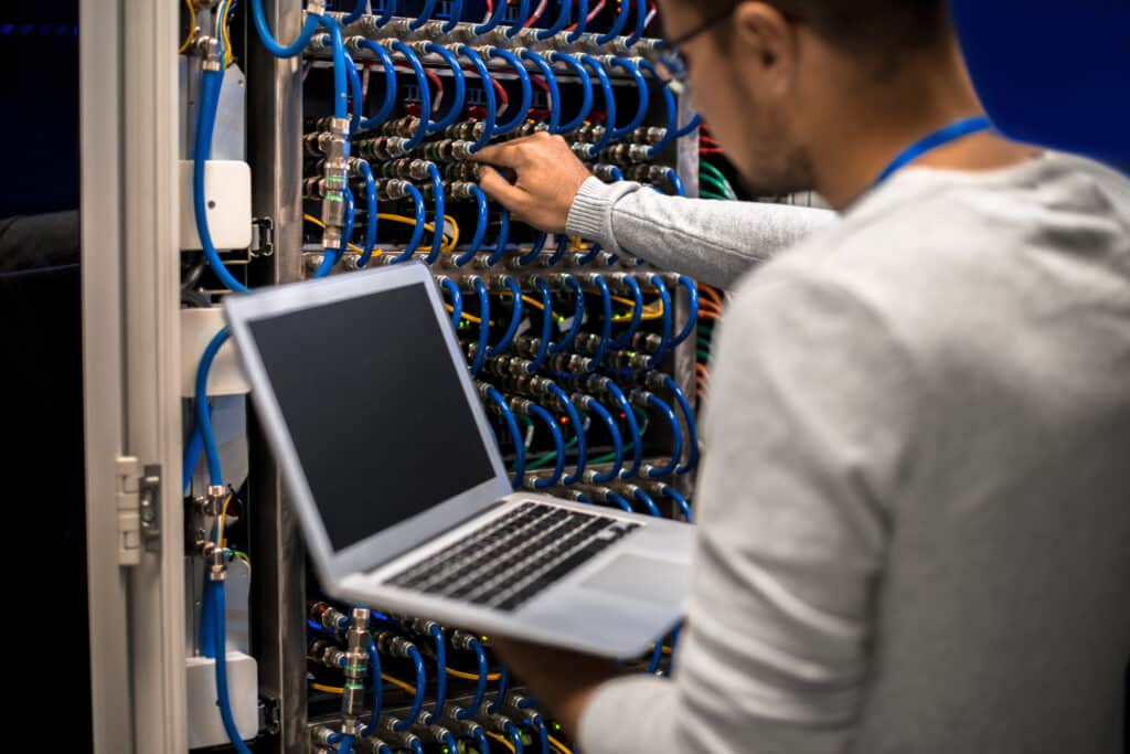 A social media manager working with a laptop in a server room.