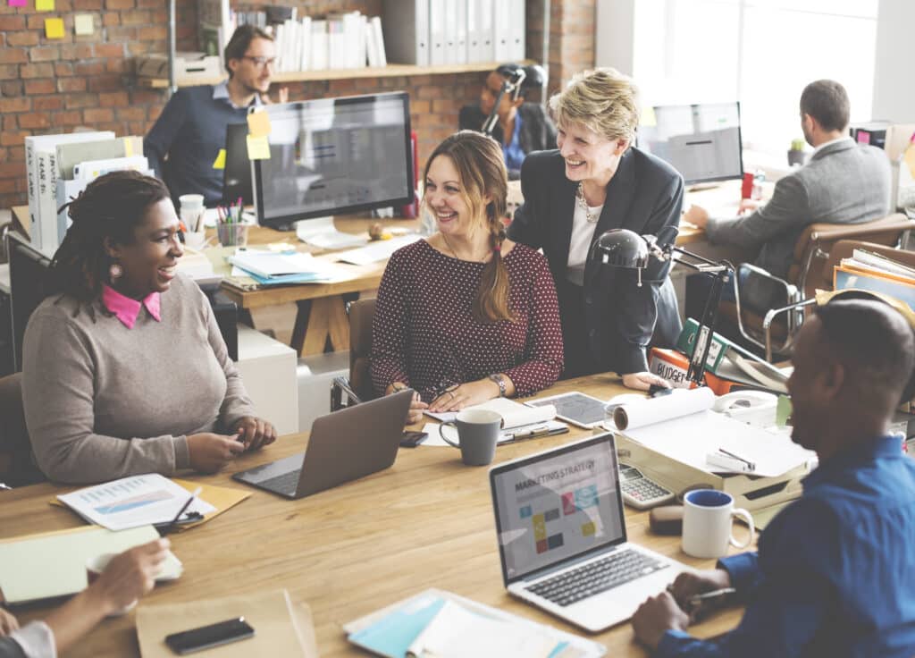 A group of people discussing digital marketing strategies at an office table.