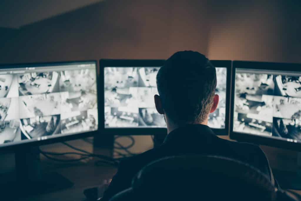 Rear back behind view of his he professional expert supervising remote, panel using safety system technology equipment night shift company safety support at workplace workstation