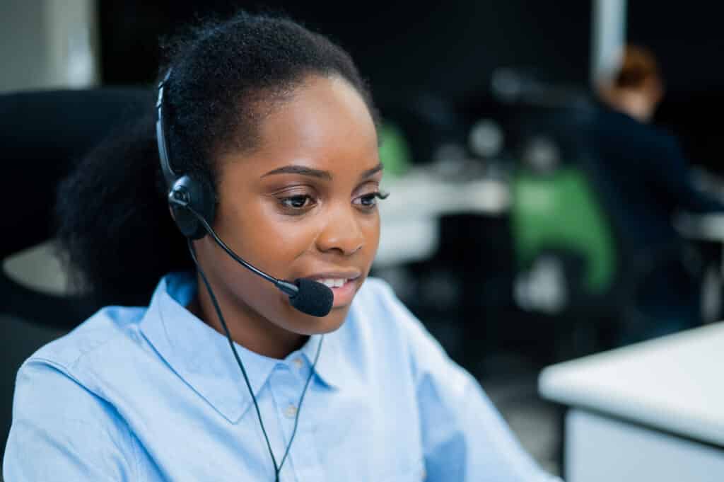 African young woman talking to a client on a headset.