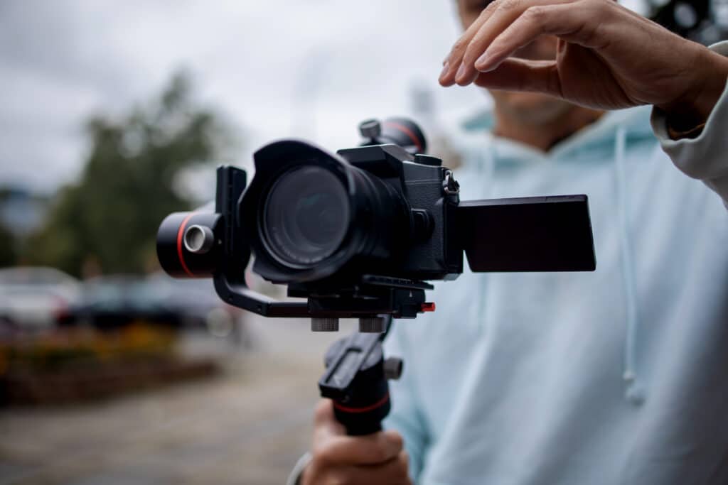 Young Professional videographer holding professional camera on 3-axis gimbal stabilizer. Pro equipment helps to make high quality video without shaking.